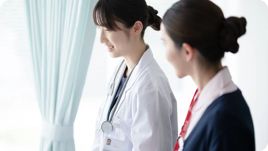 入職後の研修にて、先輩スタッフが隣に寄り添い、優しく笑顔で見守りながら指導する様子