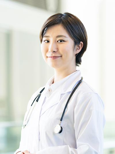 ⾸に聴診器をかけ、前を向いて微笑む⼥性医師のイメージ