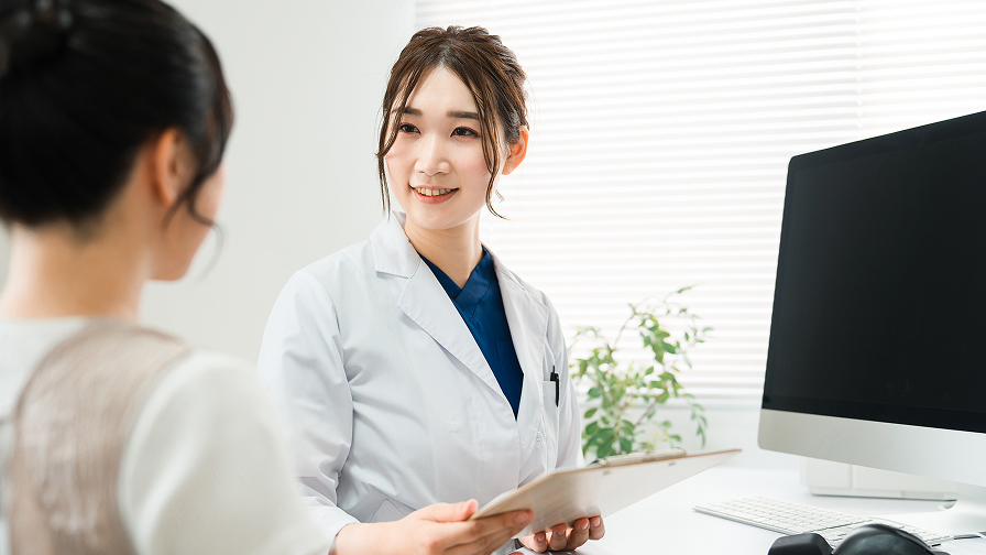 患者の話を丁寧に聞き、優しくわかりやすく説明する女性医師の診察風景
