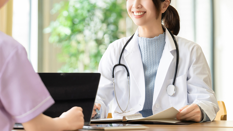 明るい雰囲気のなか、笑顔で優しく患者のカウンセリングを行う女性医師