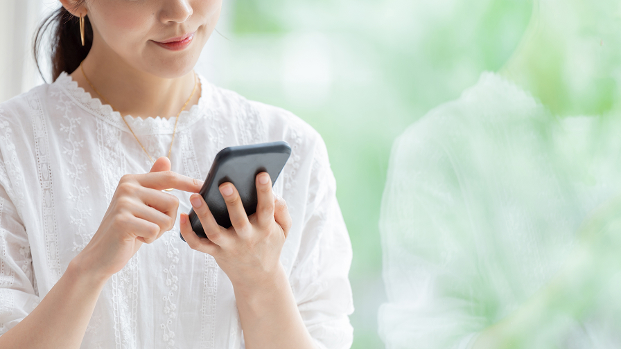 スマートフォンでWeb予約をする女性